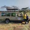 Una pareja en una excursión para ver la migración de los cinco grandes y los ñus descansa en un vehículo turístico en Maasai Mara