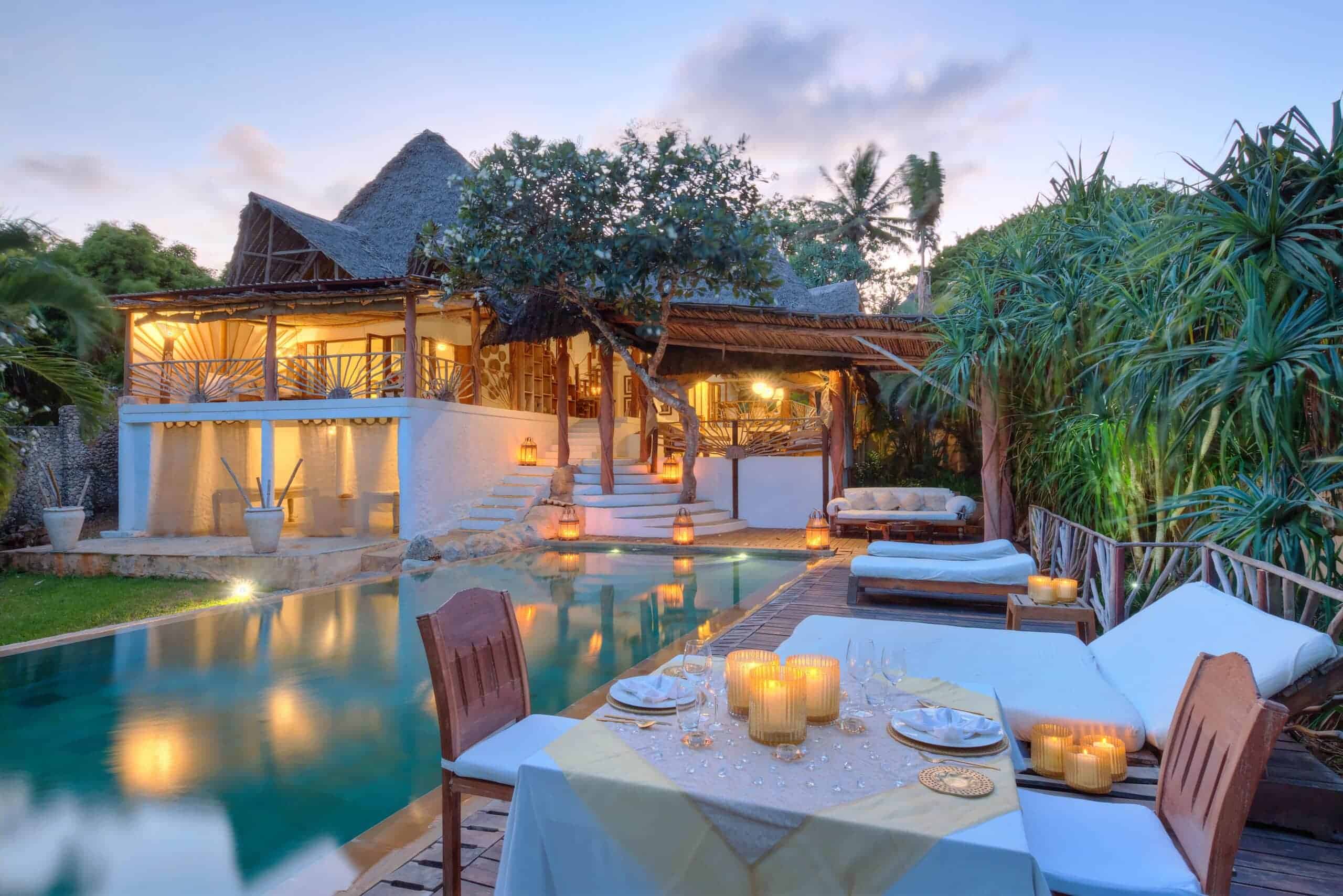 Dining setup next to the pool with exterior views of Alfajiri Beach Villa