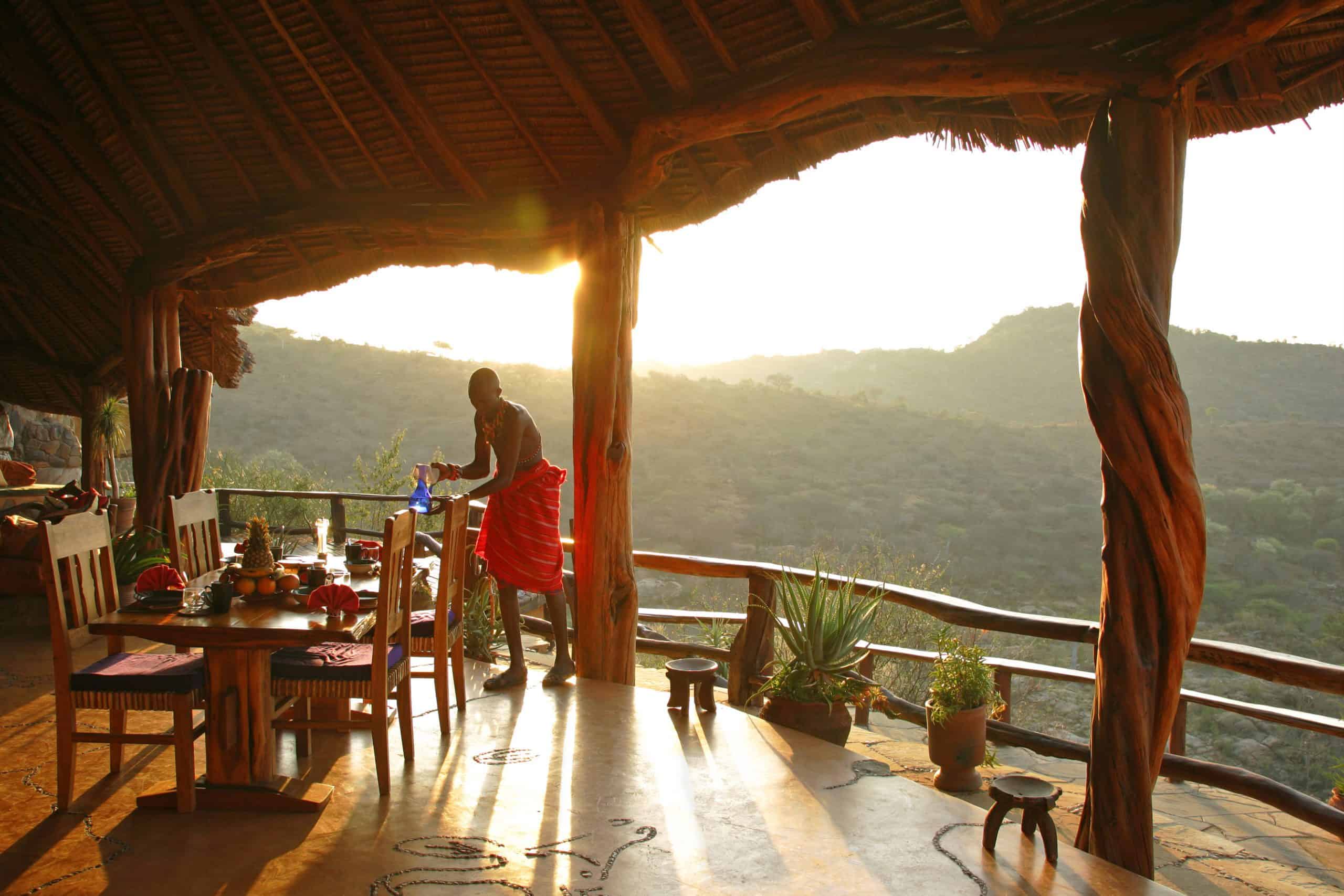 Dining setup with views of the mountains and wilderness with Masai Warrior setting up the table