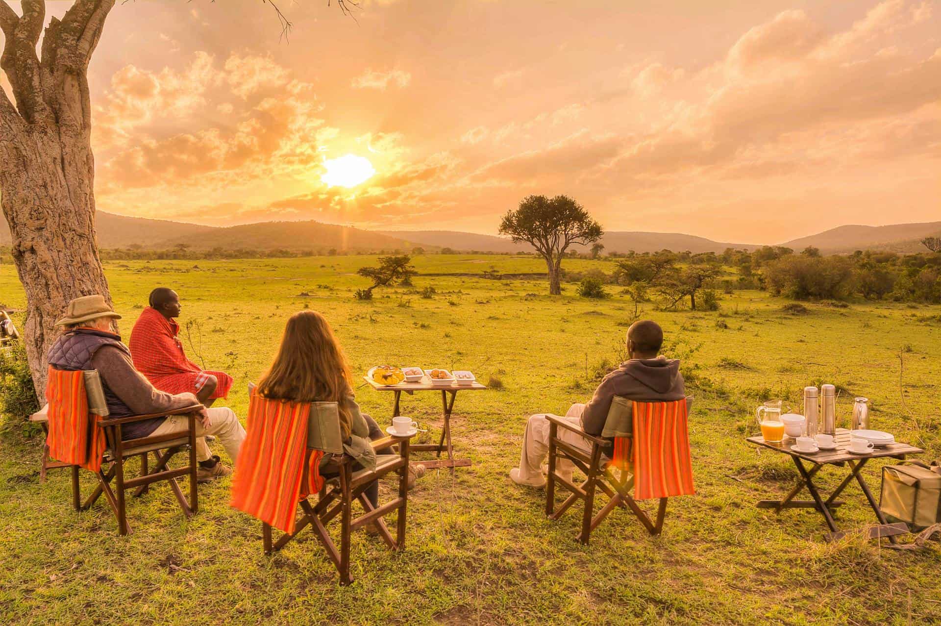 Turista disfrutando de cócteles al atardecer en las llanuras abiertas de Maasai Mara tras una viaje de cinco grandes y observar la fauna africana en la reserva.