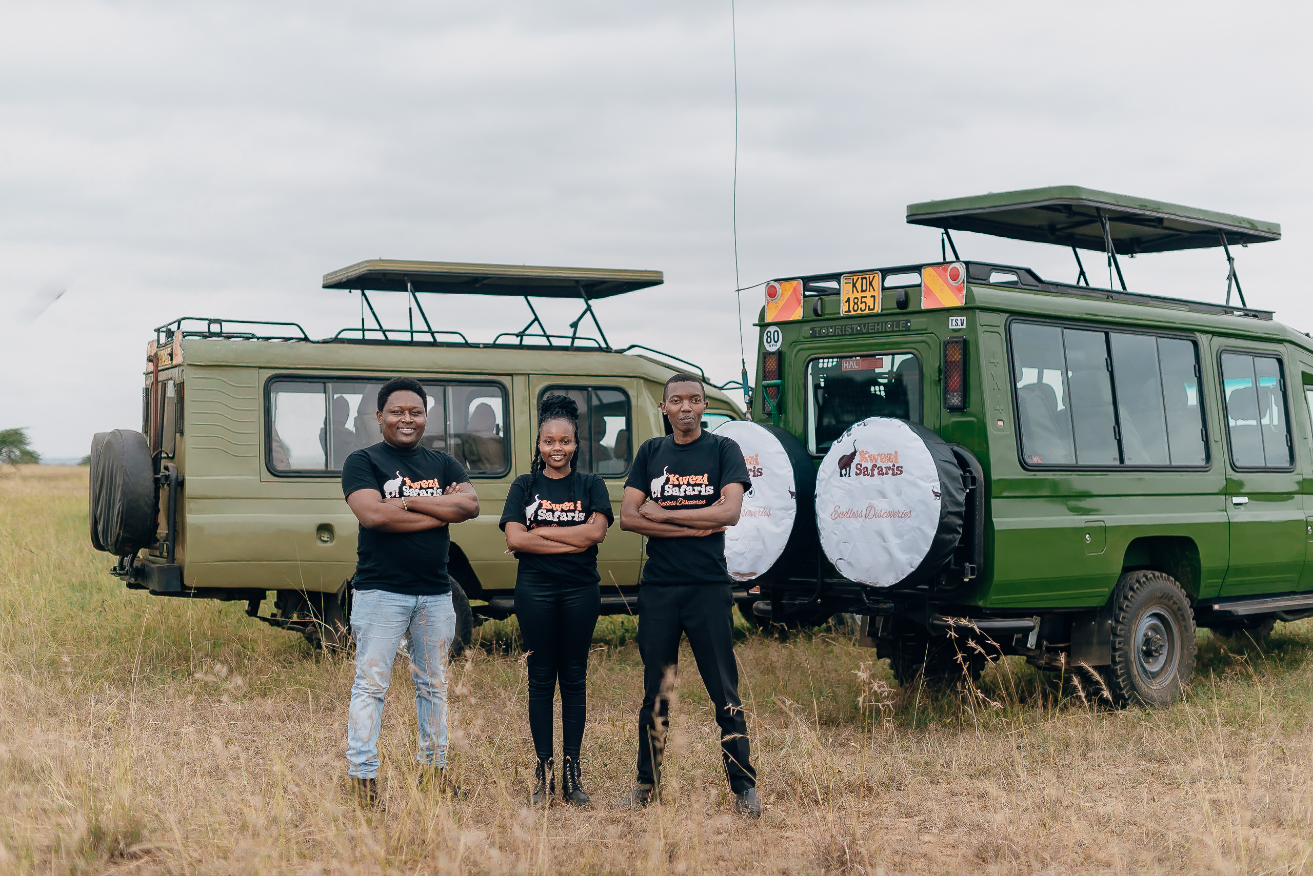 Kwezi Safaris Team Members with Safari Landcruiser on the background